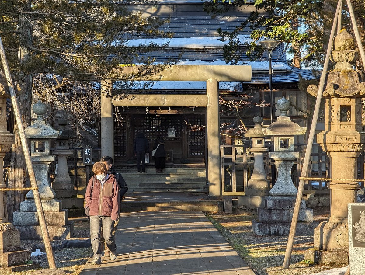 上杉神社の石鳥居と拝殿へ続く参道。両脇に石灯籠が並ぶ冬の境内