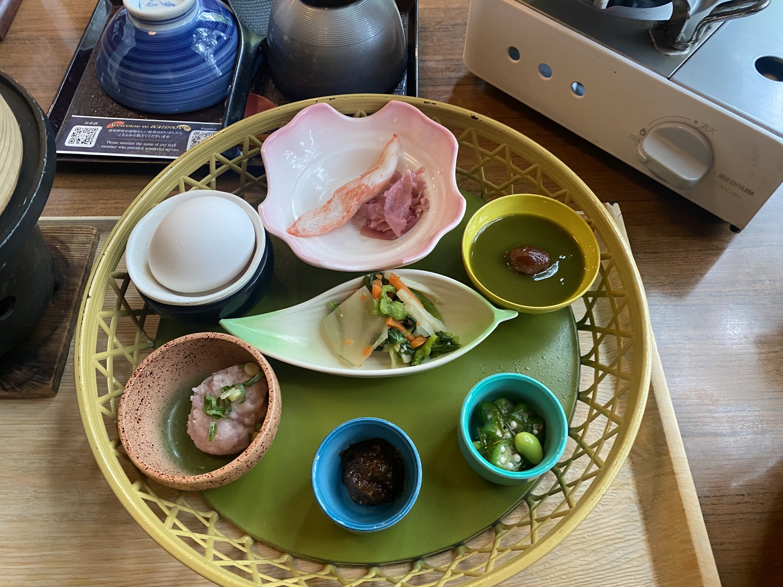 朝食のかご盛り小鉢（温泉玉子・まぐろたたき・土佐あかうし肉味噌・抹茶ようかんなど7品）