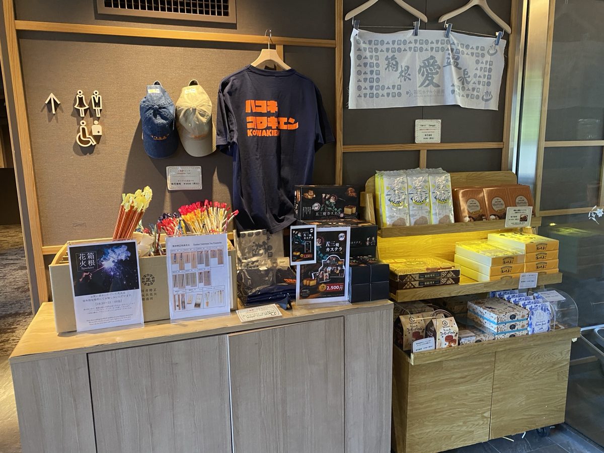 4階ロビーの売店コーナー。オリジナルのキャップ・Tシャツ・手ぬぐい、箱根の菓子、手持ち花火が棚に並ぶ|箱根ホテル小涌園